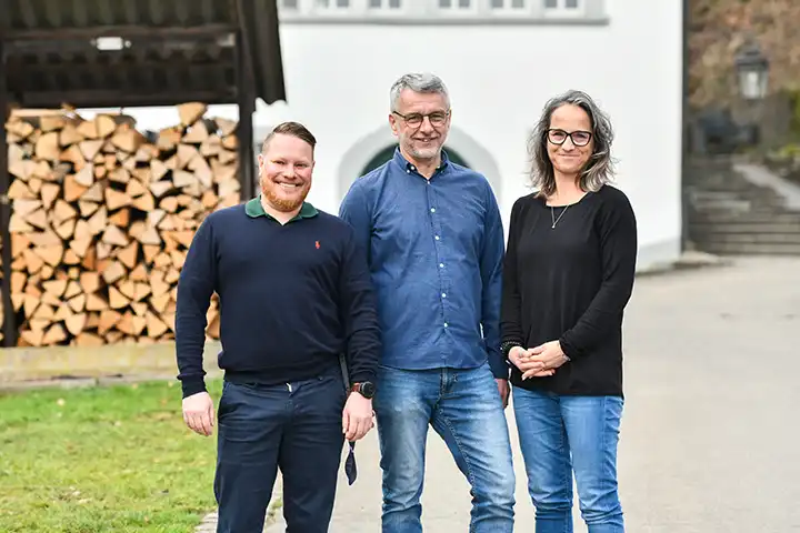 Drei Personen des Reha-Teams stehen vor dem Hauptgebäude