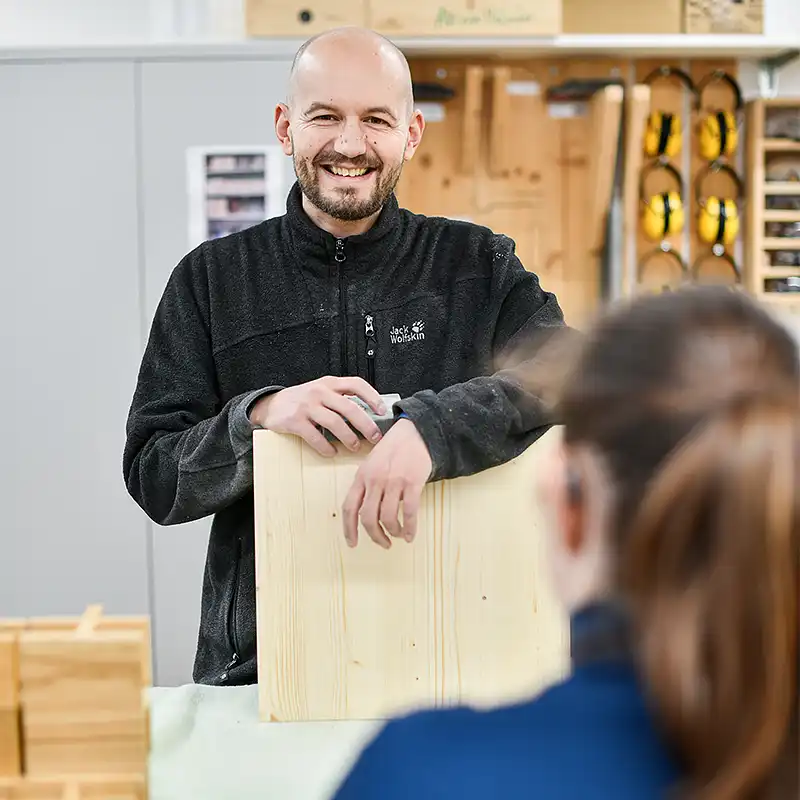 Mann mit Glaze und kurzem Bart bei der Holzarbeit